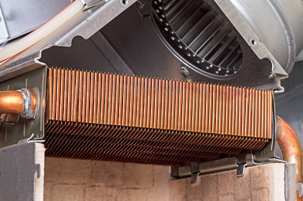 Close-up view of a furnace heat exchanger showing copper fins inside a residential heating system.