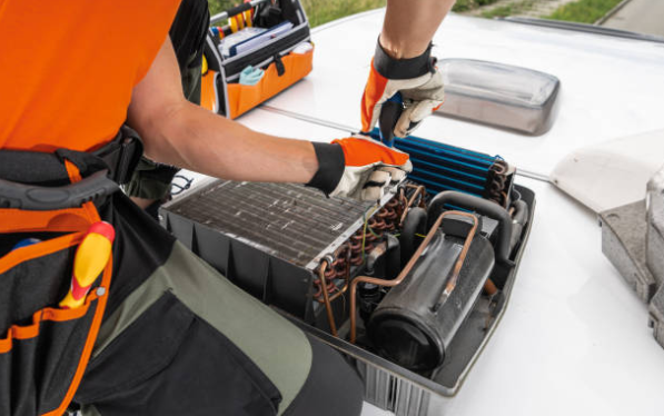 A technician servicing an outdoor air conditioning unit by inspecting internal components during HVAC maintenance.